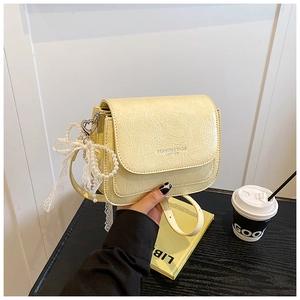 Détail du petit sac bandoulière jaune clair avec breloque perle et nœud en dentelle