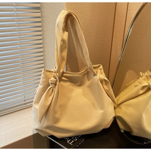 Detail of minimalist cream canvas tote bag featuring stylish knot bow shoulder strap design