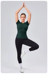 Deep green crew neck yoga tee shown in a tree pose to highlight high elasticity and fit