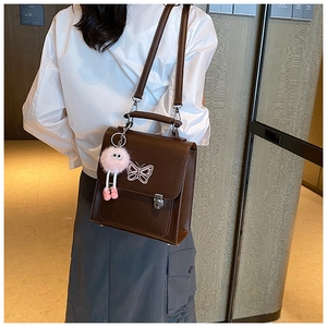 Vue détaillée du sac bandoulière vintage marron foncé avec broderie papillon et pendentif