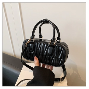 Close-up of black quilted patent leather bag with gold hardware and wrinkled texture