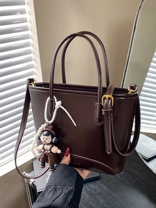 Sac seau minimaliste en cuir marron foncé avec bandoulière et pendentif décoratif