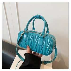 Detail of bright blue quilted leather handbag with gold zipper and dual handles