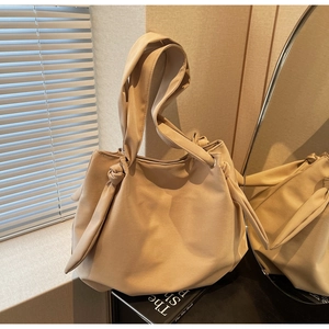 Close-up of beige faux leather tote bag showing knotted strap detail and soft texture