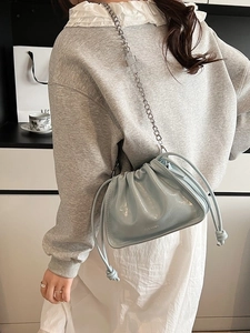 Light blue glossy leather bucket bag with silver chain strap worn by a model