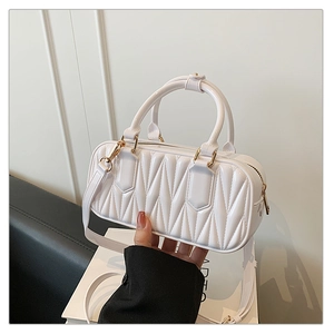 Detail of white quilted Boston bag with glossy wave texture and gold hardware