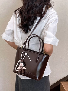 Sac fourre-tout marron chocolat brillant avec breloque perle porté par un mannequin