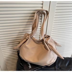 Detail of soft beige hobo tote bag featuring minimalist knotted shoulder strap design