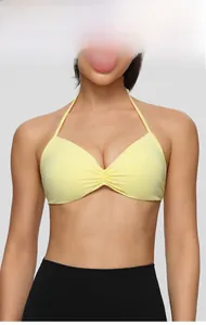 Detail of light yellow halter sports bra featuring gathered ruched center and elastic fabric