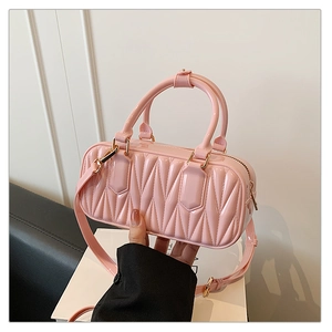 Detail of pink quilted synthetic leather handbag with golden hardware and adjustable strap