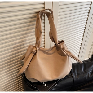 Detail of khaki tote bag featuring pleated design and large decorative shoulder strap knots