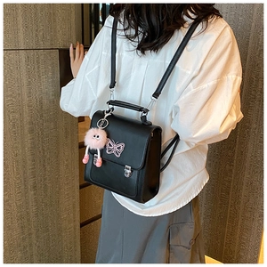 Détail du sac à dos en cuir noir avec broderie papillon rose et breloque en peluche