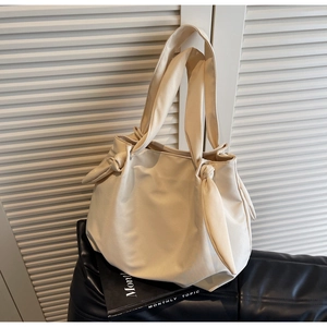 Detail view of the knotted shoulder strap and soft cream leather on a large tote bag