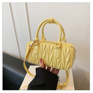 Detail of light yellow mini Boston bag with V-shaped quilted texture and top handles