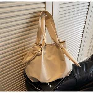 Detail of minimalist cream tote bag showing knot handle design on soft leather texture