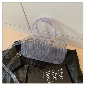 Detail of transparent purple PVC crossbody bag featuring quilted texture and gold metal clasp