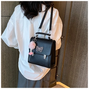Détail d'un sac à dos noir en cuir PU avec badge papillon et pendentif en peluche rose