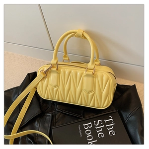 Detail of yellow matelassé crossbody bag with polished synthetic leather and top handles