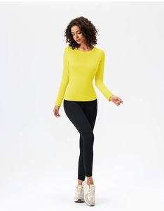 Slim fit yellow long sleeve yoga top and black leggings shown in a studio pose