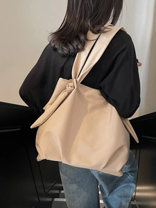 Minimalist beige tote bag with a unique knot shoulder strap shown on a model