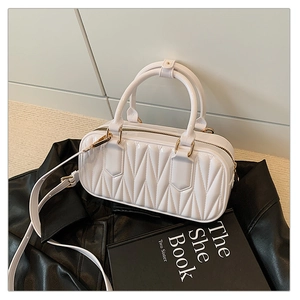 Detail of white quilted crossbody bag with gold hardware on a black leather jacket