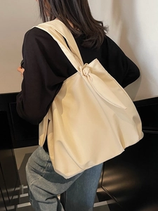 Minimalist beige oversized tote bag with knot strap detail worn by model for daily commute