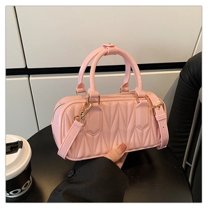 Detail view of light pink quilted jelly bag featuring a round handle and gold hardware