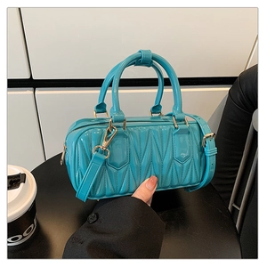 Detail of lake blue quilted crossbody bag with shiny finish and gold-tone hardware