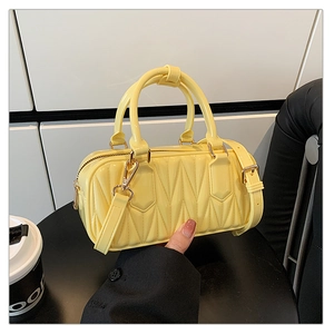 Detail of yellow pleated handbag showing shiny texture and metallic gold zipper hardware