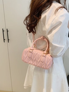 Pink pleated crossbody bag with top handles and gold hardware shown on a model