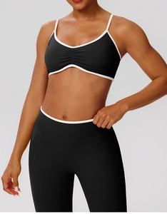 Detail of black sports bra with ruched V-neck and white contrast trim edging