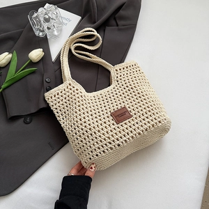 Close-up of beige crochet woven tote bag featuring a premium brown leather logo patch