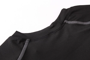 Detail of the crew neck and flatlock seams on a black men's compression workout shirt