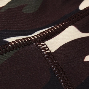 Detailed close-up of high-density flatlock stitching on camo print yoga shorts fabric