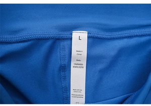 Detail view of the inner laundry tag on blue high-waist yoga shorts showing size L and fabric