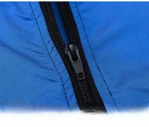 Detailed close-up of smooth black nylon zipper on bright blue sports jacket fabric
