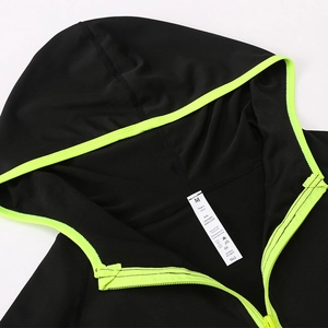 Détail d'un sweat de sport noir avec bordure vert fluo et étiquette de composition de tissu