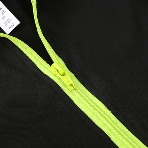 Détail de la fermeture éclair en résine vert fluo sur veste de sport noire femme