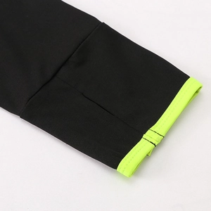 Détail de la manche d'une veste de sport noire avec poignets côtelés vert fluo et coutures