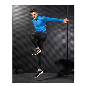Men's blue half-zip sweatshirt and black leggings shown during an athletic jumping pose