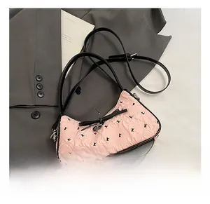 Close-up of pink pleated underarm bag featuring black bow detail and heart pendant