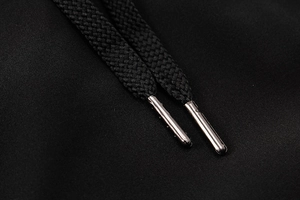 Détail du cordon noir avec embouts métalliques argentés sur un short de sport pour homme
