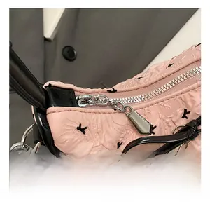 Close-up of pink quilted handbag featuring black cat embroidery and silver heart charm