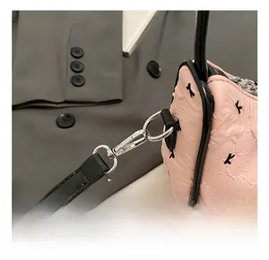 Close-up of pink quilted fabric shoulder bag with silver metal hooks and K-letter pattern