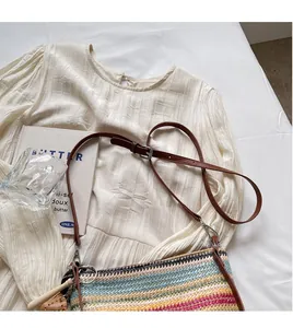 Detail of adjustable leather strap and colorful striped woven pattern on a shoulder bag