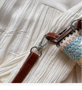 Detailed close-up of silver metal buckle on a colorful striped woven straw tote bag