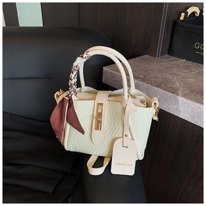 Détail d'un sac à main tissé blanc cassé avec foulard en soie et fermoir doré