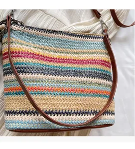 Detail of colorful striped woven tote featuring leather straps and ethnic beaded pendant