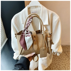 Détail du sac seau tissé kaki avec fermoir doré et foulard en soie décoratif élégant