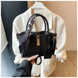 Détail du sac seau noir tressé avec foulard pied-de-poule et fermoir rotatif doré